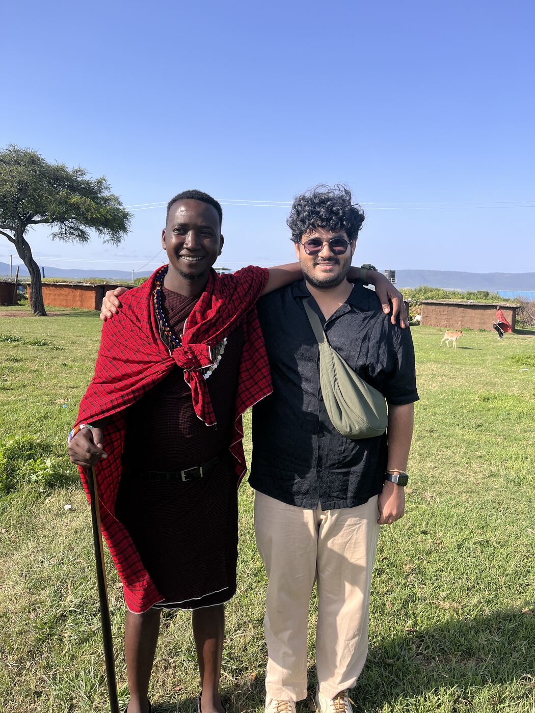 Anmol with a friend in a red shuka on open grassland